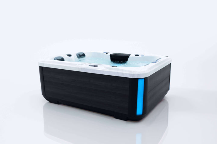 Angled side view of Luso Spas The Eden Hot Tub filled with bubbling water and blue LED corner lighting on a white background.