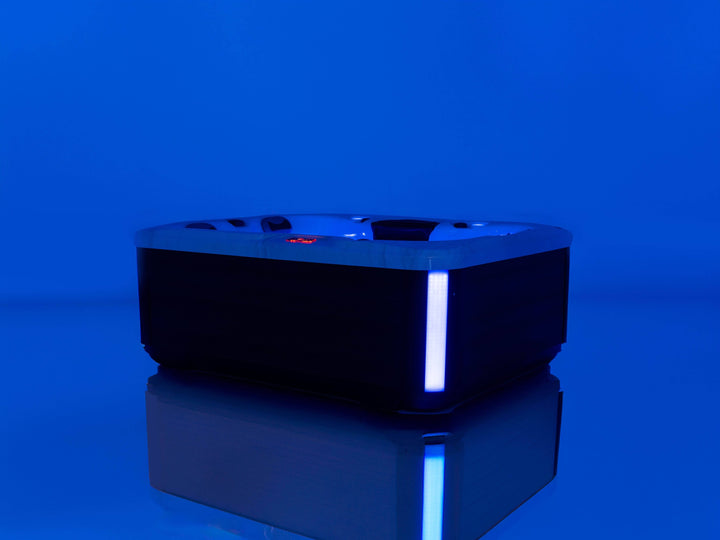 Luso Spas The Eden Hot Tub illuminated with blue LED lighting in a dark blue setting.