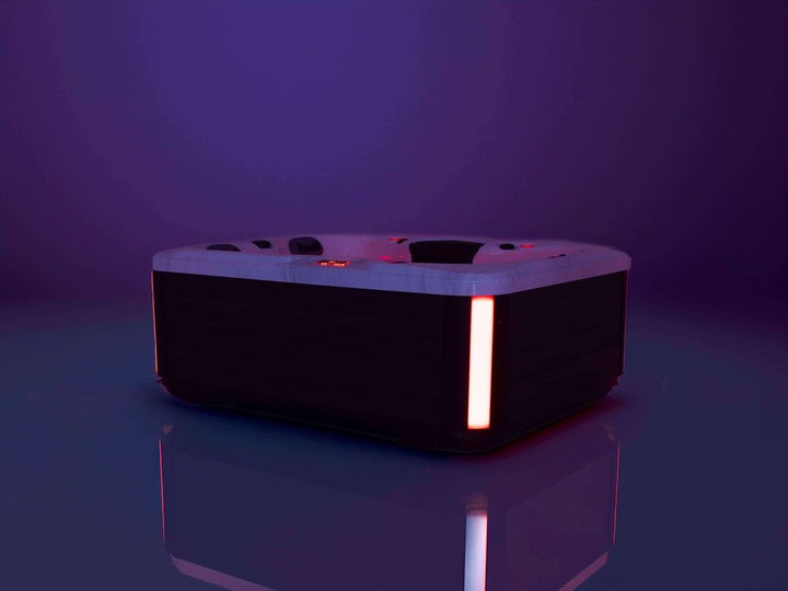 Luso Spas The Eden Hot Tub illuminated with red LED lighting in a dark purple setting.