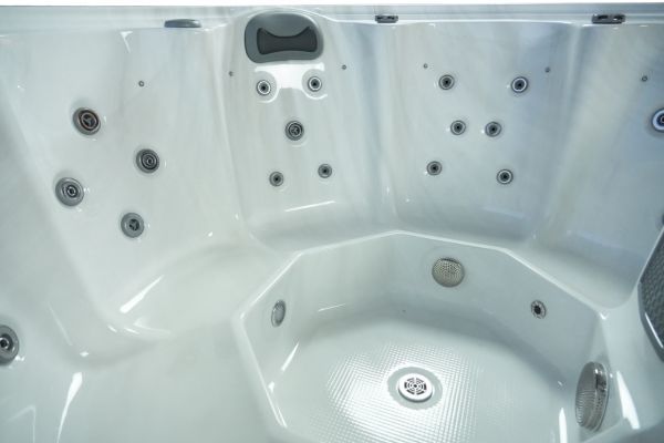 Side interior view of Luso Spas The Orb Hot Tub in white acrylic finish showing contoured seats, massage jets, and drainage outlet.