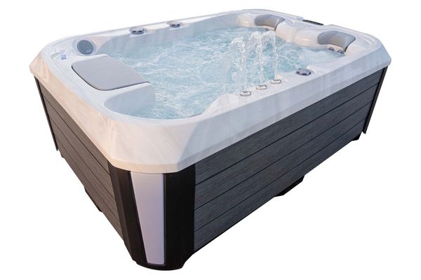 Luso Spas The Platinum 1 Hot Tub in white marble finish filled with water and jets running, showing cascading water streams on a white background.