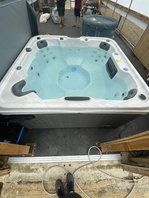 Outdoor installation of Luso Spas The Venice Hot Tub filled with clear blue water and surrounded by wooden decking and equipment.