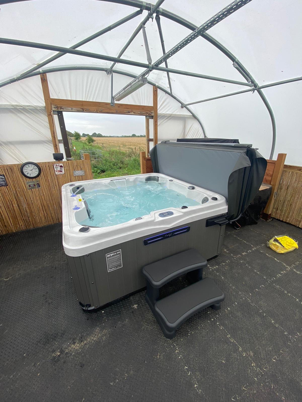 Luso Spas The Venice 2 Hot Tub installed indoors with grey exterior panels and black steps beside it.