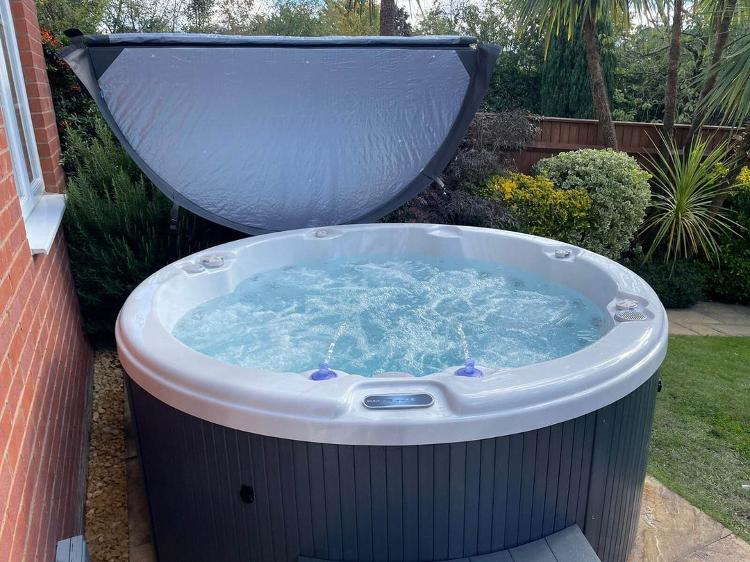 Close-up front view of Luso Spas The Zodiac Plug & Play Hot Tub filled with water and jets running in a garden setting.