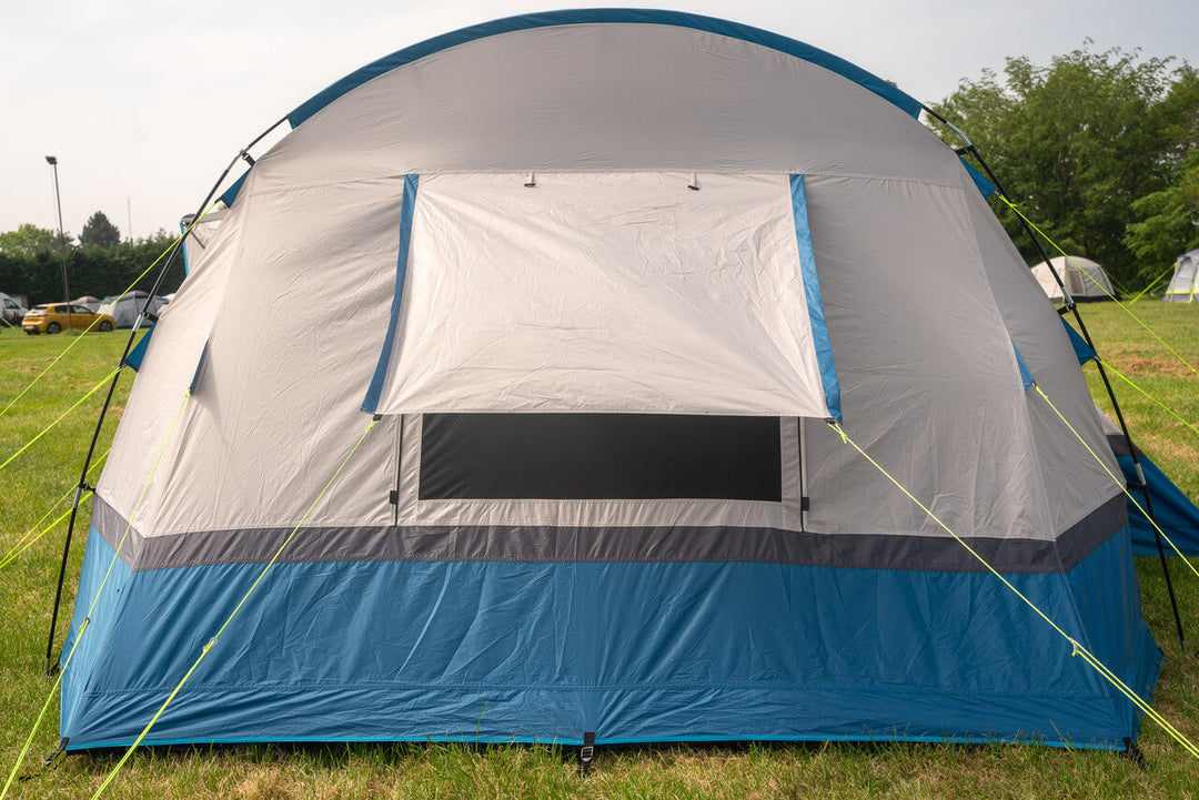 Side view of the OLPRO Cocoon V2 awning with large window flap open, pitched on grassy field.