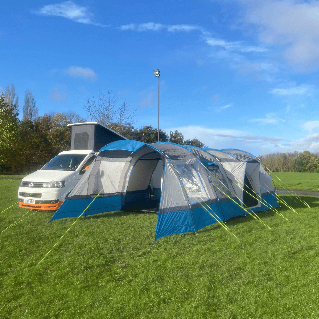 OLPRO Cocoon V2 campervan awning fully pitched next to a campervan on a grassy field.