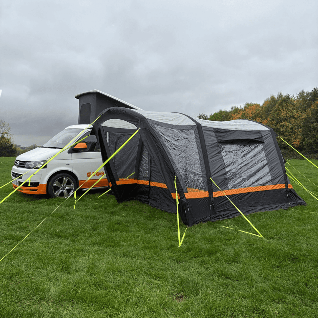 OLPRO Hanley Breeze driveaway awning attached to a Volkswagen campervan on a grassy field.