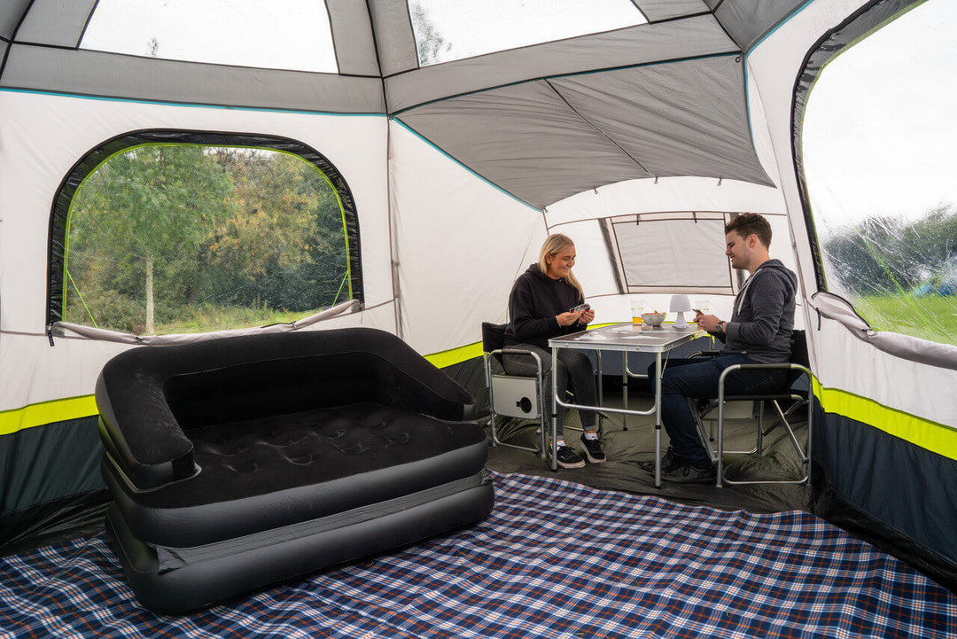 Inside the OLPRO Hive Campervan Awning with two people playing cards at a table on a campsite.