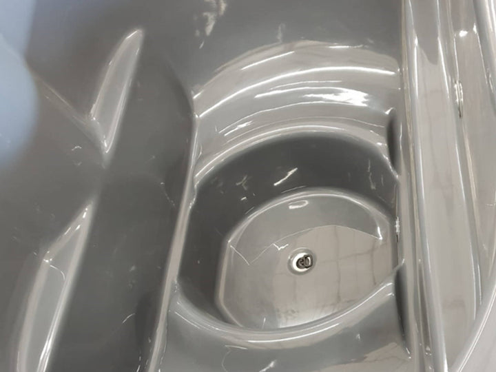 Close-up of grey Ofuro Cold Tub interior showing built-in ergonomic seat and center drain on a white background.