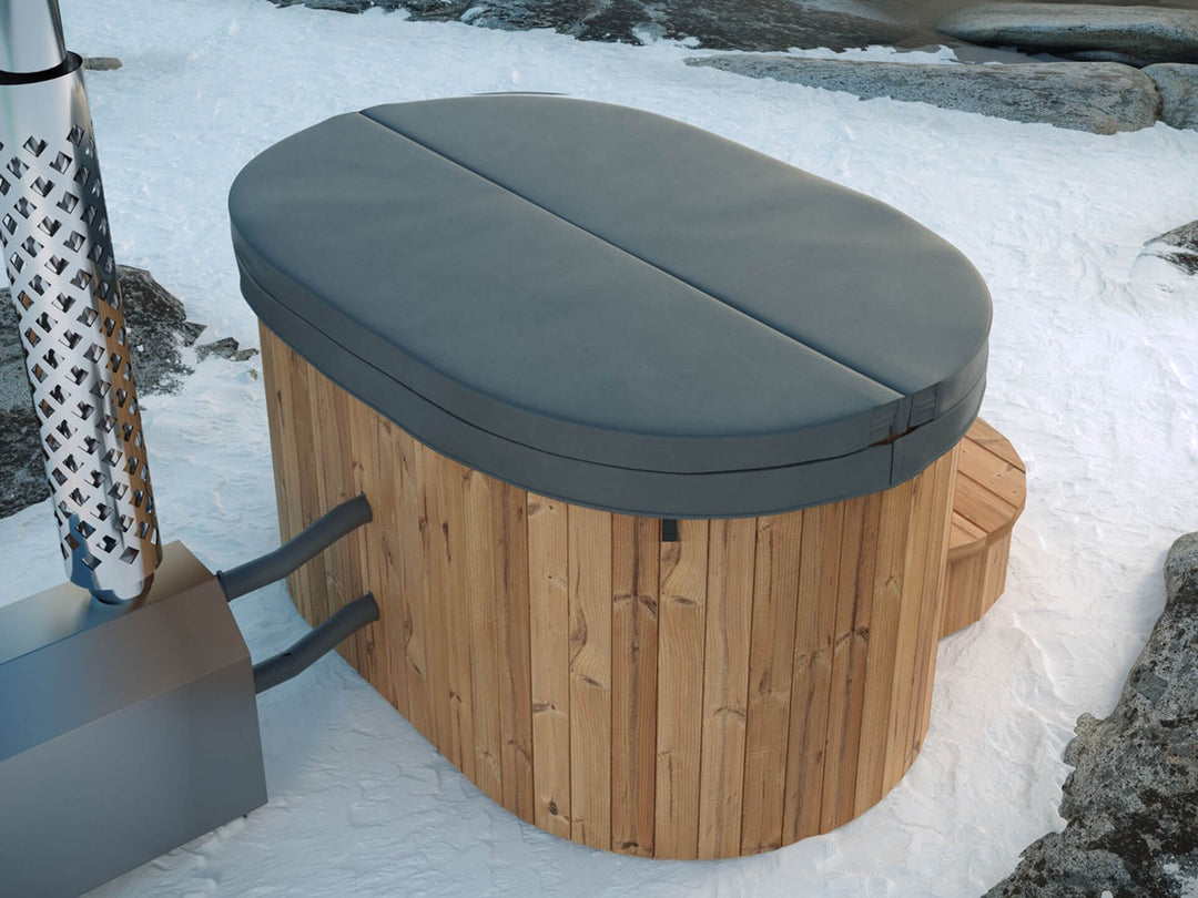 Ofuro Cold Tub with grey insulated cover, natural wood exterior, and metal heater placed on snowy ground with rocks.