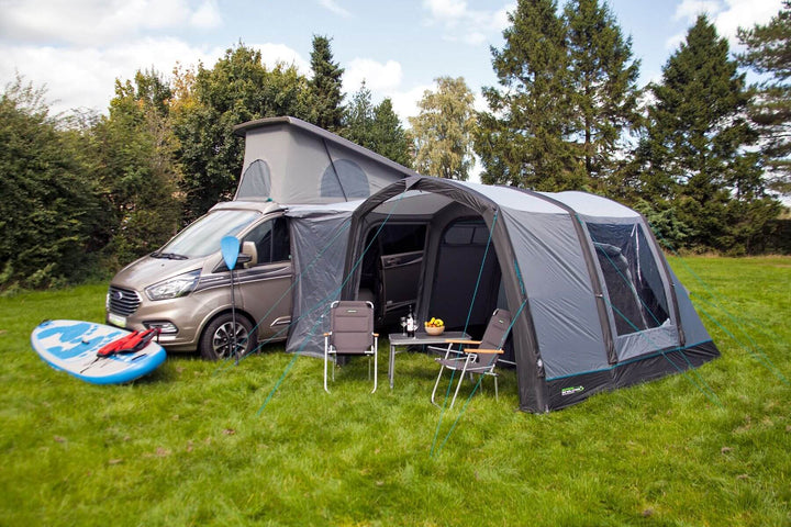 Close angled view of the Outdoor Revolution Cayman Air T3 Lite driveaway awning connected to a campervan with outdoor seating and camping accessories.