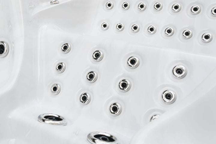 Close-up of stainless steel massage jets inside the Luso Spas The Party Pool Hot Tub, on a white acrylic surface.