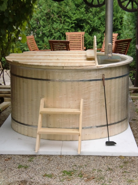 Unwrapped Viking Industrier Polypropylene hot tub with light wood exterior and small ladder, in a garden with chairs and greenery.