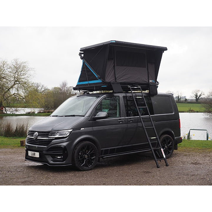 Skypod Lair rooftop tent with black frame and blue highlights mounted on a campervan in outdoor surroundings.