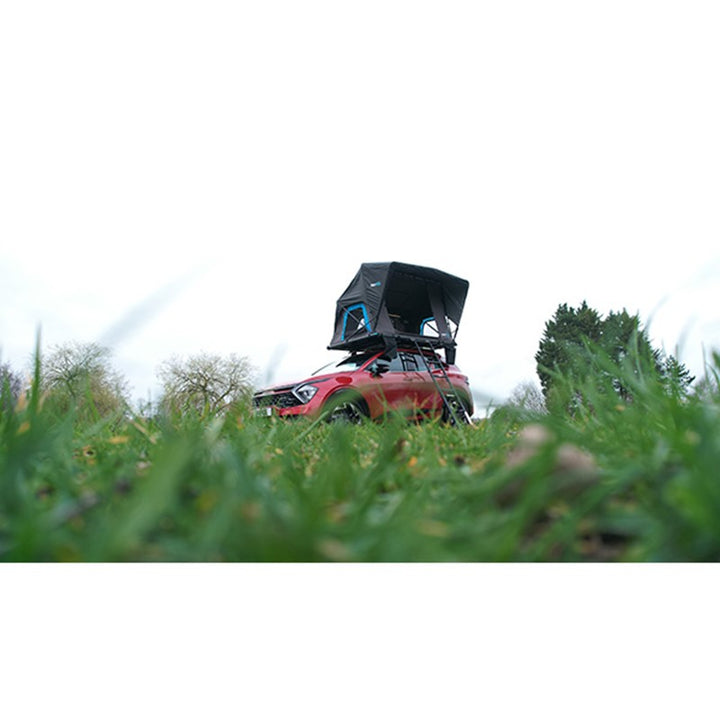kypod Rapide rooftop tent on a red SUV parked near a grassy field, perfect for weekend camping trips.