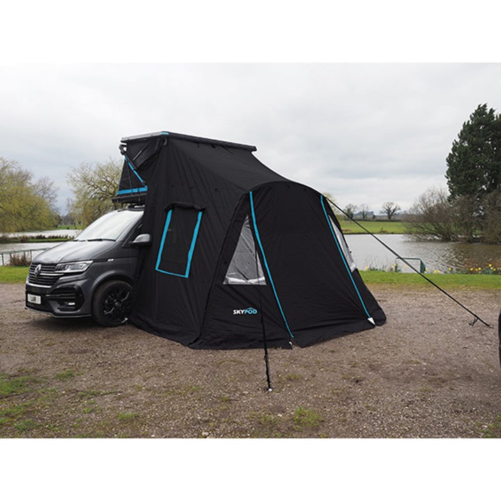 Skypod rooftop tent with full annex extension attached to a campervan in an outdoor campsite setting.