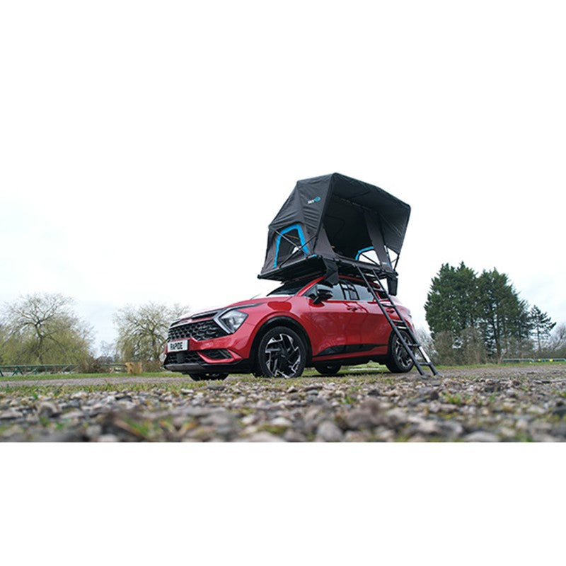 Red car with Skypod Rapide rooftop tent open for camping outdoors in a scenic area.