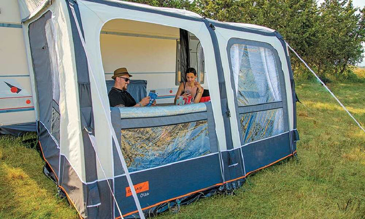 Two people reading inside a Soplair Olea air awning with an open window