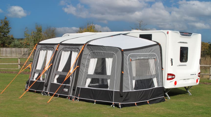 Camptech Starline Elite Infinity Pod in grey and black next to a white caravan on a grassy background.