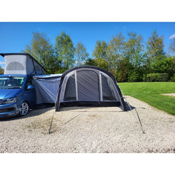 Side view of a gray and white Sunncamp Swift Motor Air Driveaway Awning attached to a blue VW campervan, showing the main entrance and awning structure