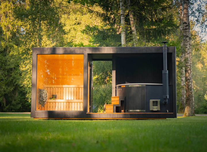 Taurus Grand Outdoor Sauna full front exterior view on grass in a woodland setting with large glass window and hot tub.
