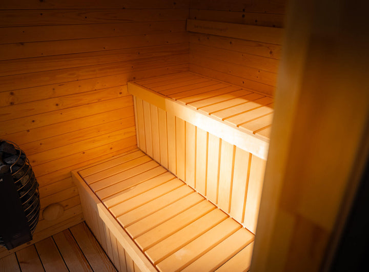 Interior bench seating inside the Taurus Grand Outdoor Sauna with light timber walls and warm ambient lighting.