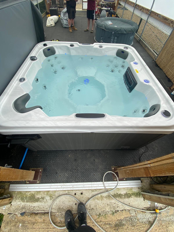 Luso Spas The Venice 2 Hot Tub filled with water and blue LED lighting inside a wooden shelter background.