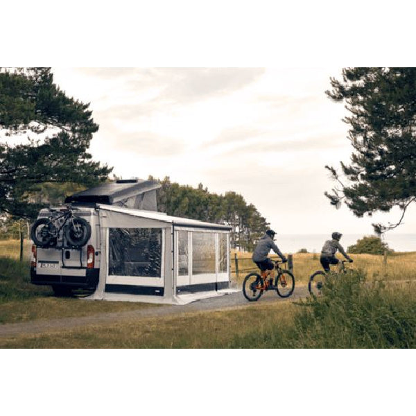 Two people on bikes cycling past a Thule G3 which is connected to a van