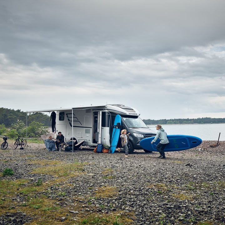 Thule awning extended on a motorhome at a rocky lakeside campsite.