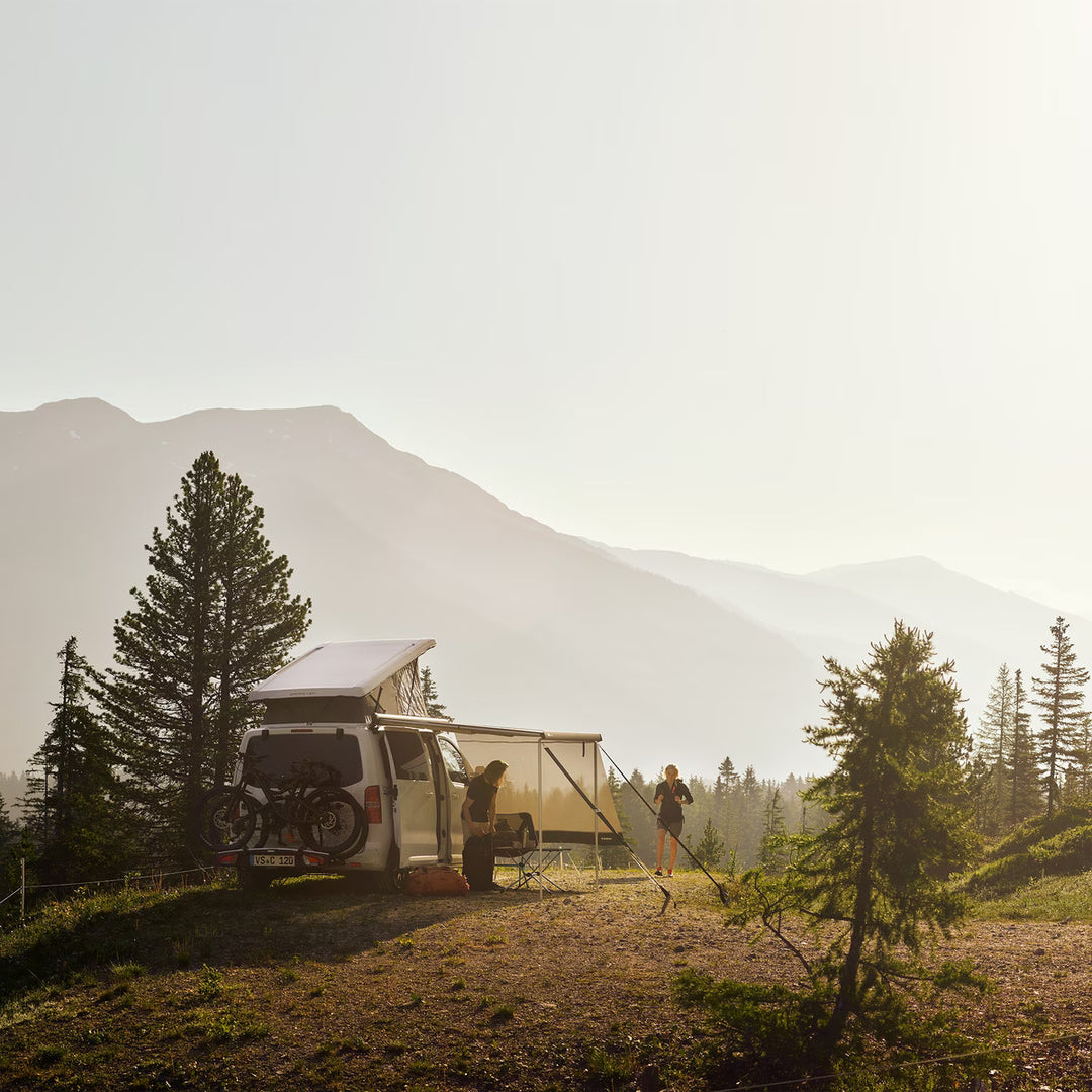 Van parked in the mountains with Thule awning extended at sunset.