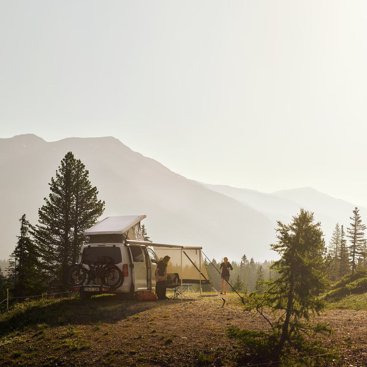 Van parked in the mountains with Thule awning extended at sunset.