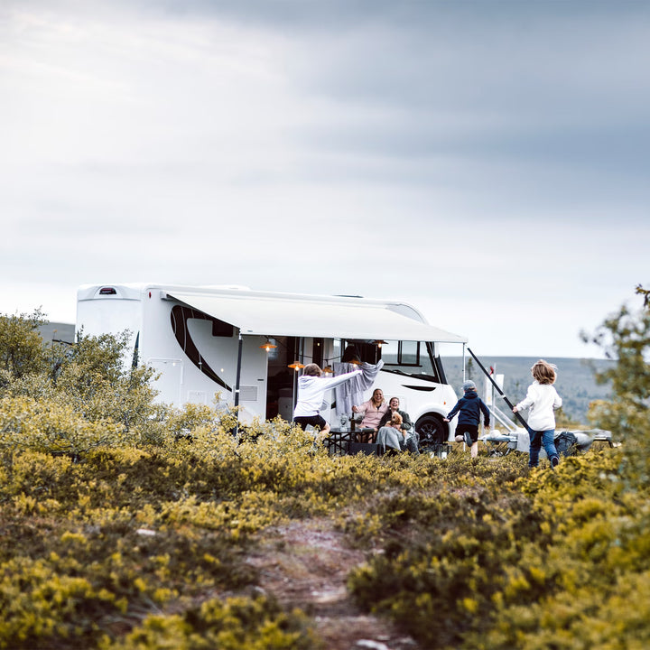 Family camping under a white Thule awning in nature.