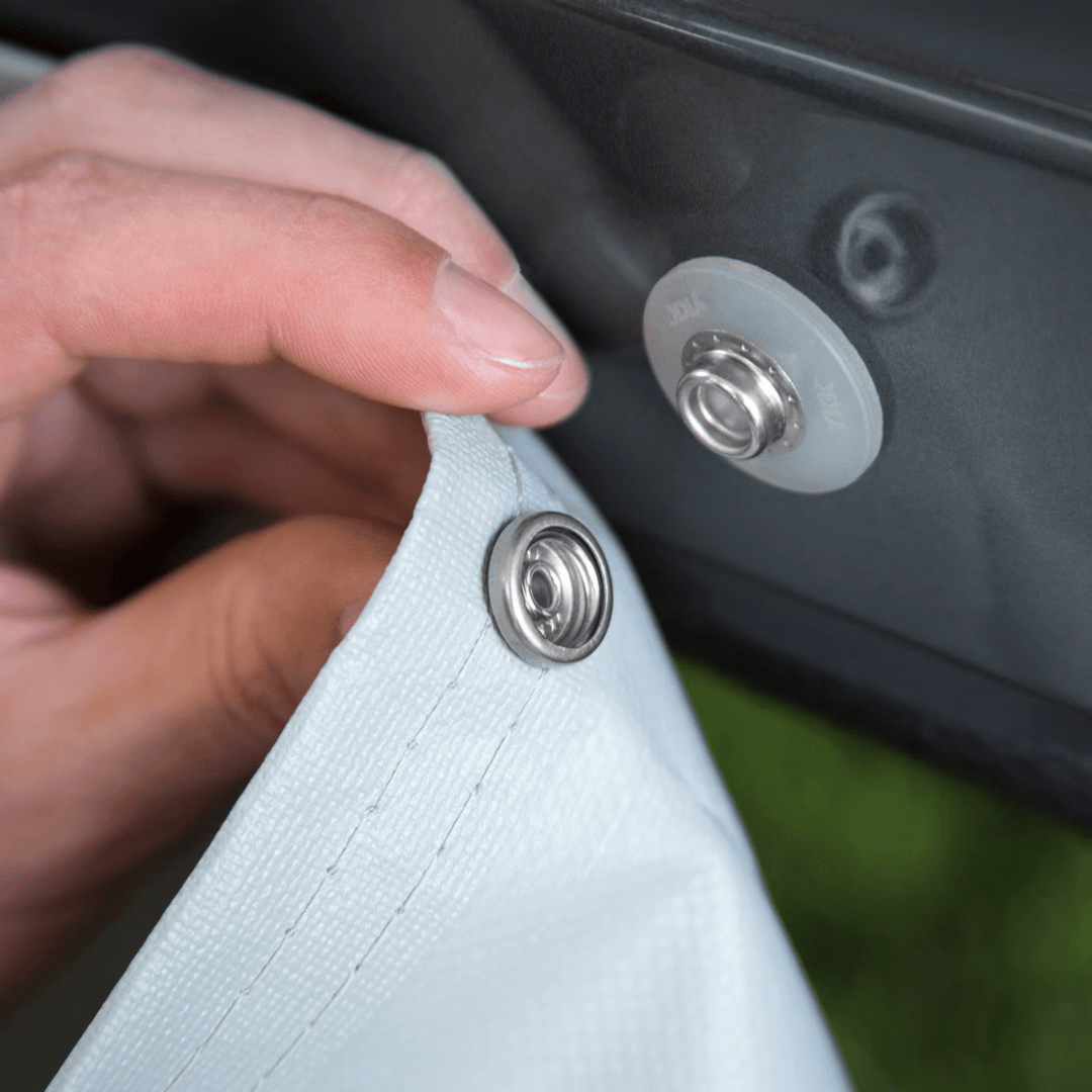 Hand attaching a Thule wheel cover snap fastener to a caravan wheel.