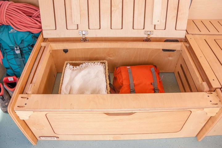 Campervan “Topo” Sofa-Bed showing large under-seat storage compartment with wooden lid open inside a campervan interior.