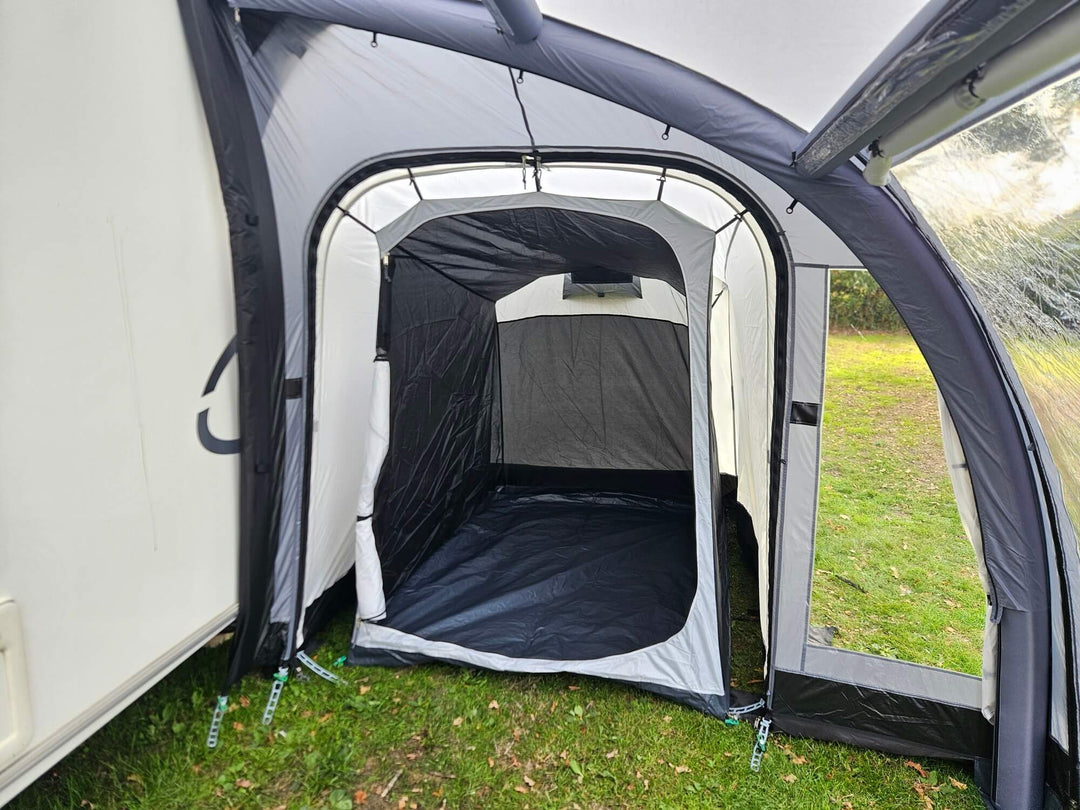 Interior view of the Sunncamp Ultima Versara Air 390 Deluxe Porch Awning showing the inner sleeping annex tent on a grassy campsite with caravan wall on the side.