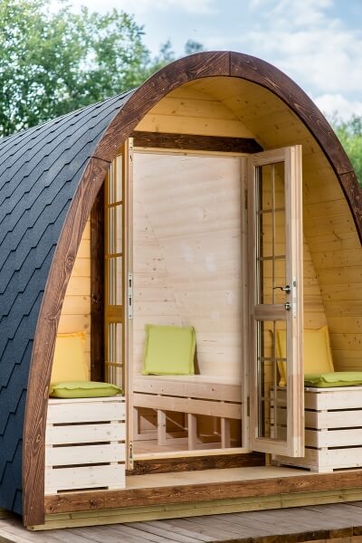 Interior view of a Viking Industrier 2.4 x 3m Camping Pod showing open doors and seating with green pillows.