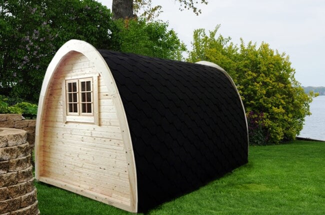 Rear side view of the Viking Industrier 2.4 x 4m Camping Pod in a natural setting with a lake in the background.