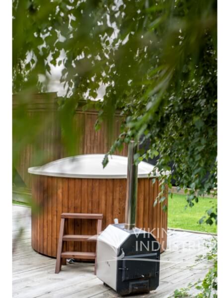 Viking Industrier Fiberglass Hot Tub with integrated heater placed on a wooden deck, partially obscured by tree leaves in a garden with a wooden fence in the background.