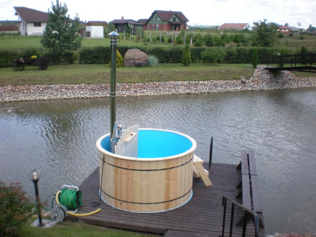 Viking Industrier Polypropylene hot tub with blue interior on a dock over a lake, with green grass and trees in the background.