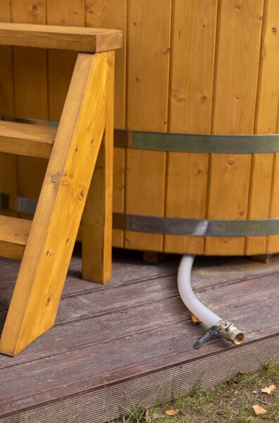Close-up of Viking Industrier oval cold tub showing the side, wooden stairs, and drainage hose, placed on a wooden deck.