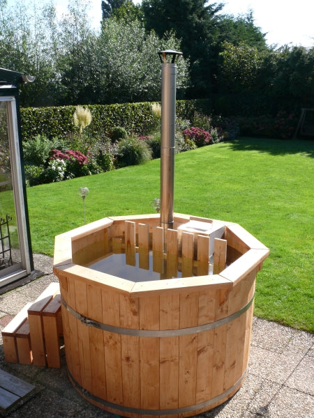 Viking Industrier Spruce hot tub filled with water, situated on a patio in a green backyard with a lush lawn and garden flowers.