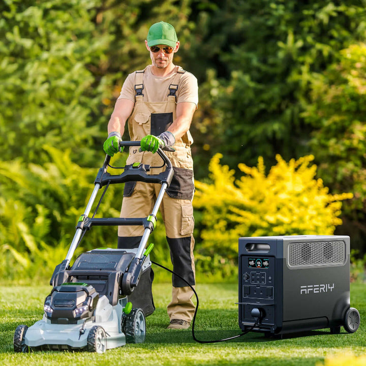 Man using a lawn mower connected to the Aferiy P310 portable power station outdoors, surrounded by greenery.