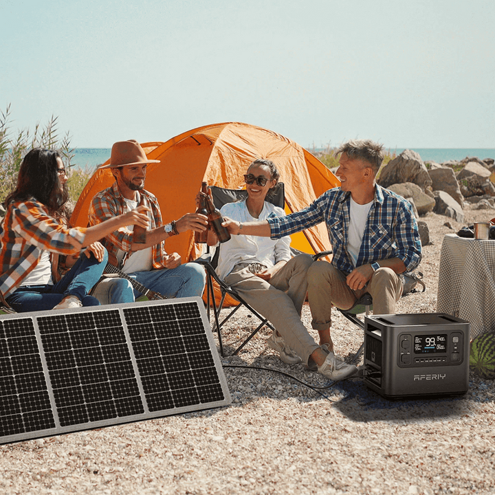 Aferiy P10 2400W Solar Generator Kit at a beach campsite with a group of friends raising drinks beside an orange tent and solar panel.