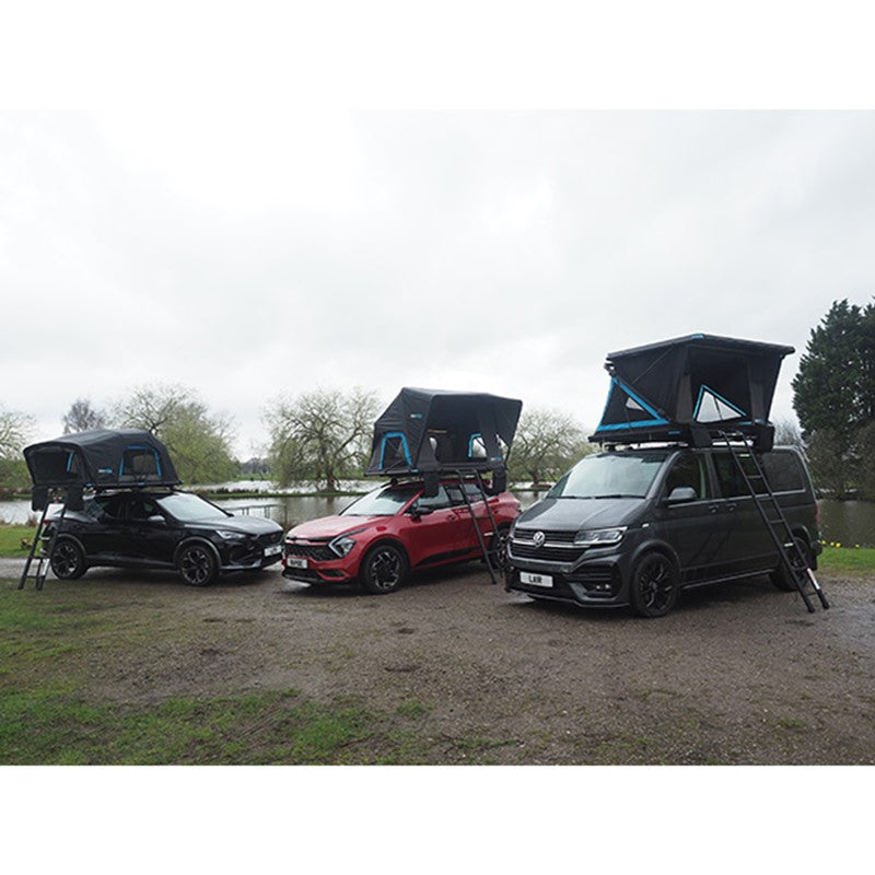 Three cars fitted with Skypod rooftop tents for families parked beside a lake in a countryside setting.
