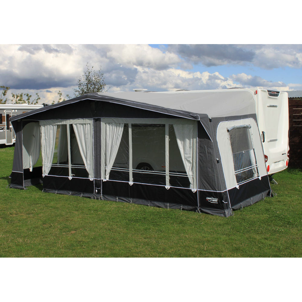 Camptech Kensington Air full caravan awning with curtained front windows and a side window, pitched on grass beside a Swift caravan