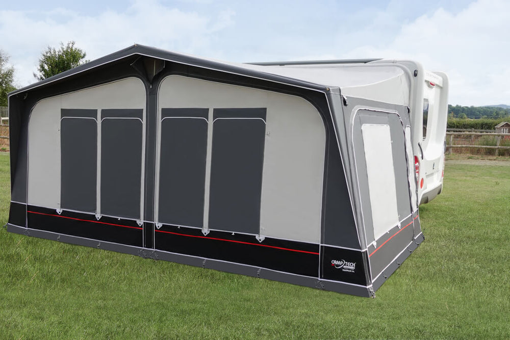 Camptech Mayfair DL awning with window blinds open beside a white caravan on a grassy campsite.