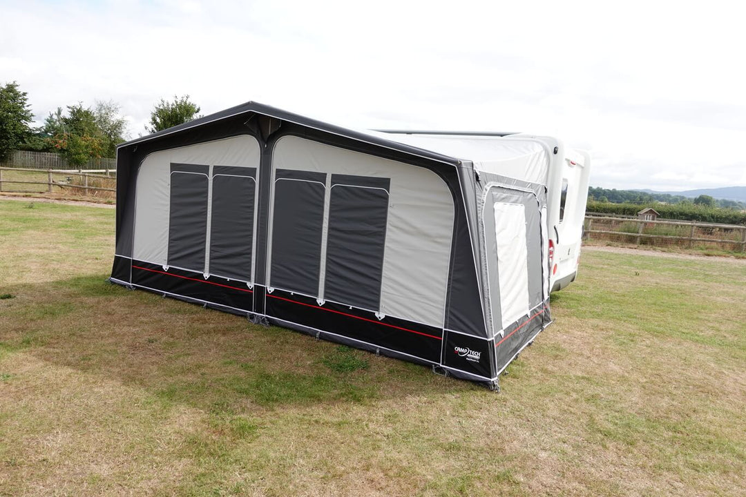 Camptech Mayfair DL caravan awning with privacy blinds closed on a green campsite with cloudy sky background.