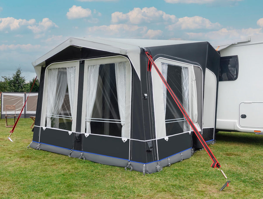 Camptech Moto Windsor caravan awning attached to a white motorhome on a grassy campsite with cloudy sky background.