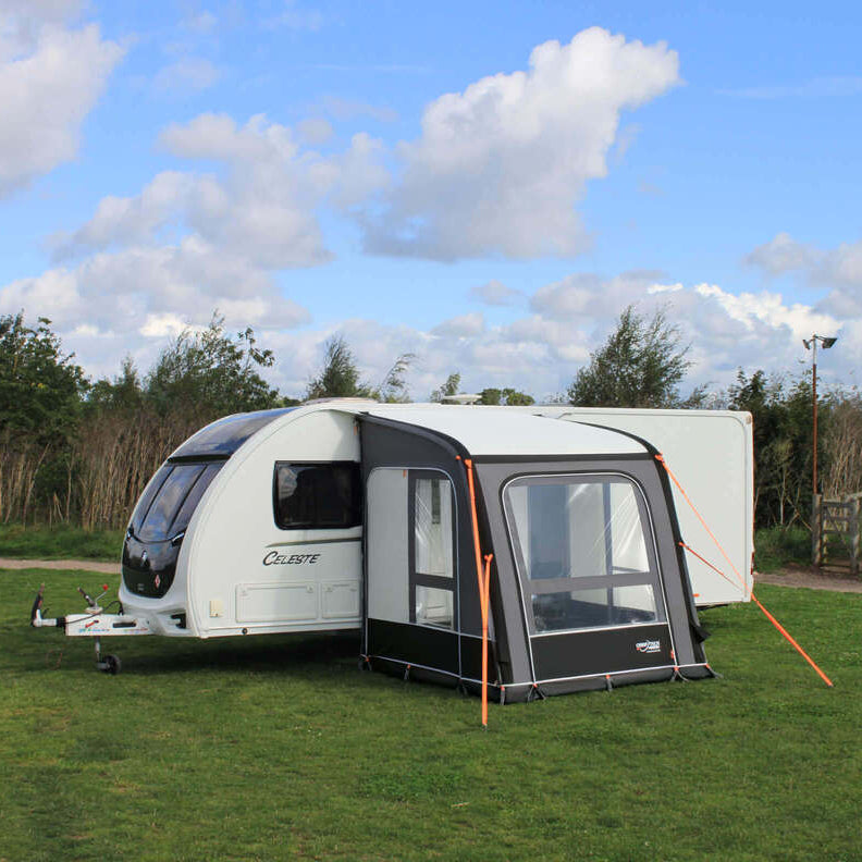 Camptech Starline Elite 200 caravan awning attached to a white caravan on a grassy campsite with blue sky background.