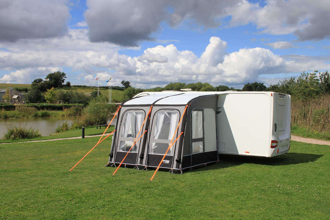 Camptech Starline Elite 300 inflatable caravan awning set up on a green campsite with lake and countryside background.